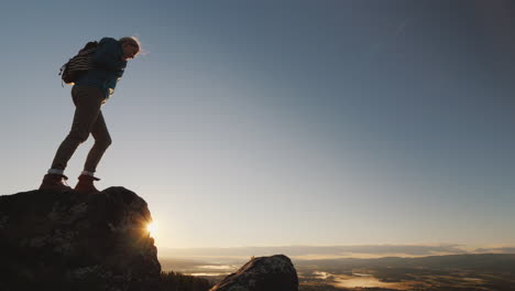 active woman reaches the top of the mountain admires the magnificent scenery of norway