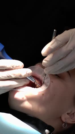 a dentist is examining a woman’s teeth, using her finger, thumb, and gestures to check the health of her dental flesh.
