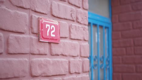 a close-up of a red brick wall with a red house number 72 plaque