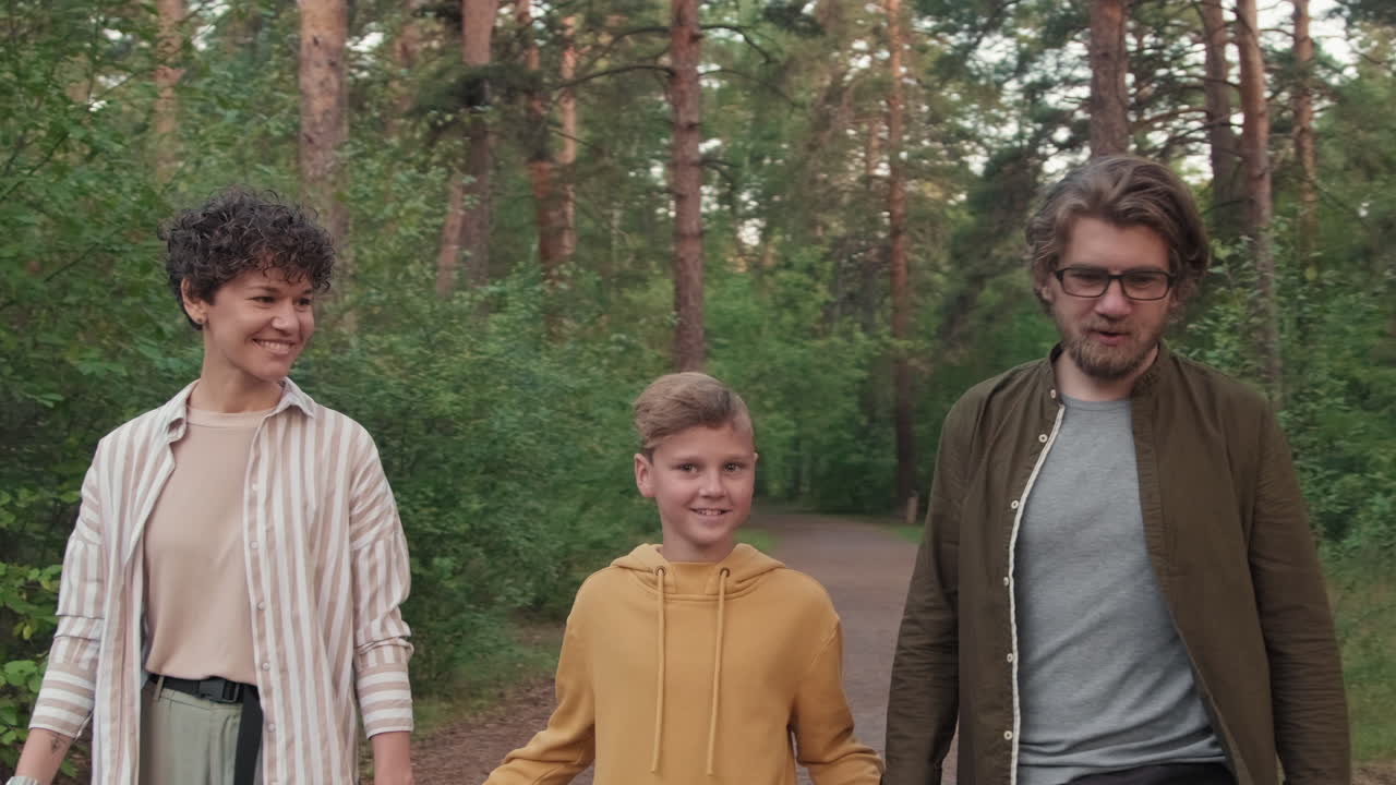 Young Family Of Three Strolling In Forest