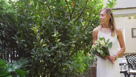 happy caucasian woman holding bunch of flowers in garden on sunny day
