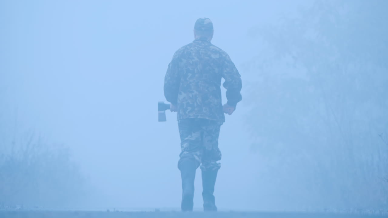 숲길에서 피 묻은 도끼를 든 살인자가 자동차 헤드라이트에 비추어 소름 끼치는 범죄 현장에 서 있다