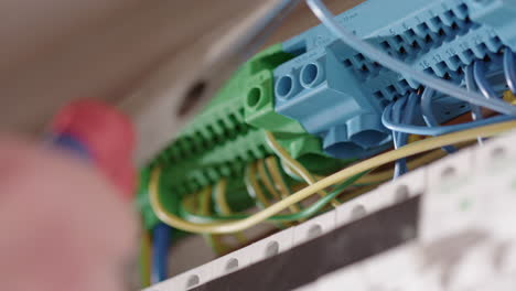 electrician uses long nose pliers to insert wires into circuit breaker, closeup