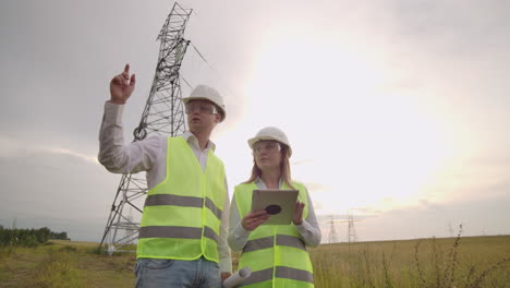 engineer and supervisor with tablet pc and the drawings are about lines and transmission towers and discuss the expansion plan and transportation energy for towns and cities