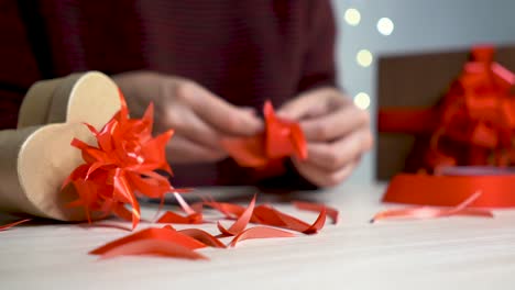 the hands of a woman preparing bows for gifts in a nice bokeh