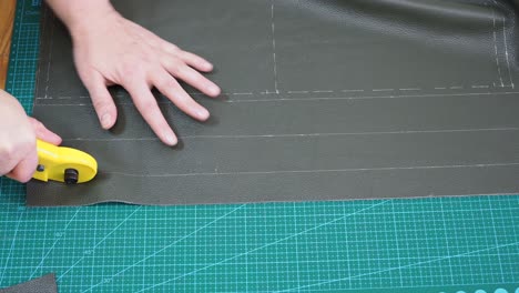 craftsman cuts green leather using rotary cutter knife