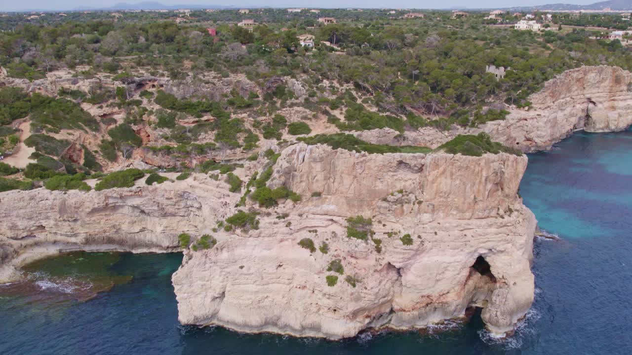 Orbit around big cliffs at S'Almonia beach Mallorca island during day time, aerial