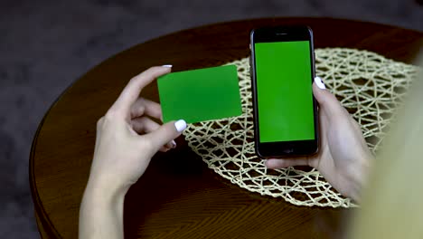 girl with a credit card and a phone. fills data close up. green screen