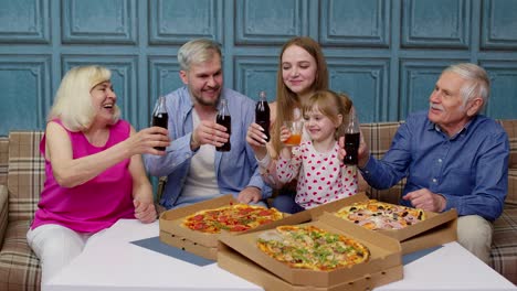 happy multigenerational family having lunch party at home, eating pizza food, raising toast together