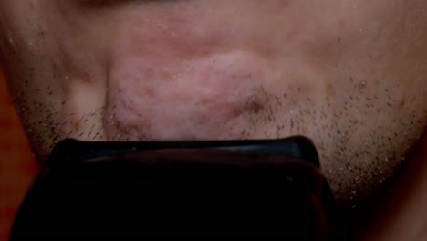 man shaving a short beard in the early morning with automatic shaving machine