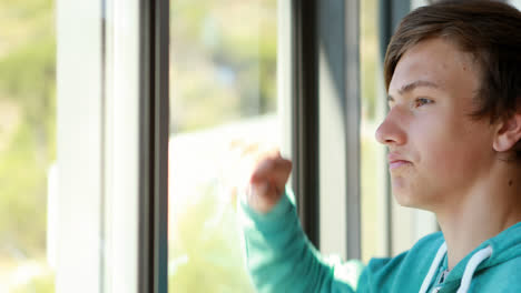 thoughtful schoolboy looking through window