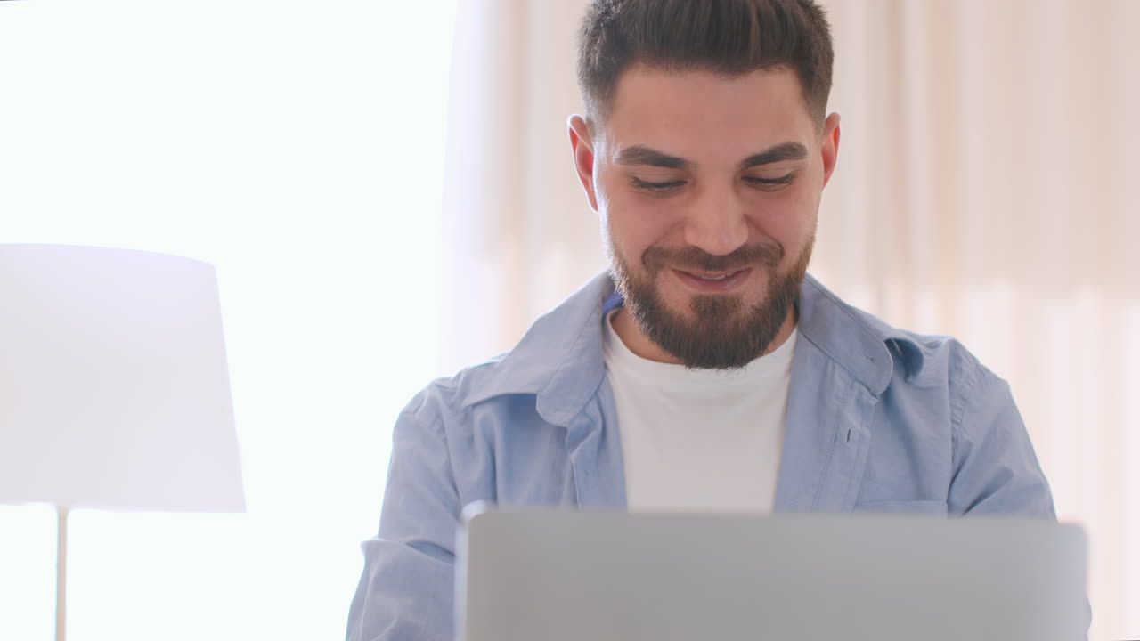Smiling Man Using Laptop at Home