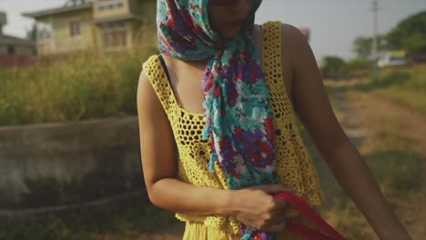 young girl or brunette woman dressed in yellow with a headscarf and sunglasses walking a dog in slow motion