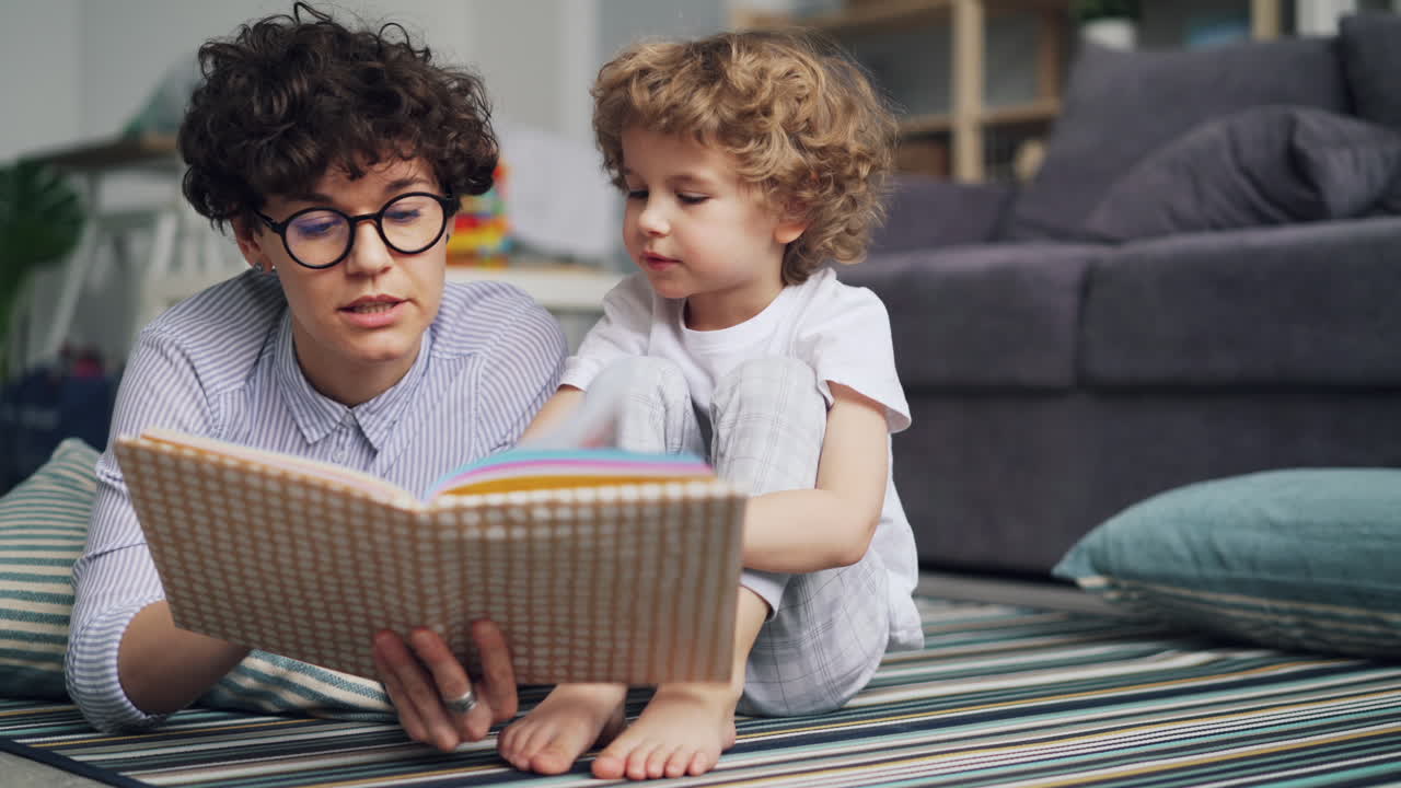 Madre e figlio che leggono insieme sul pavimento