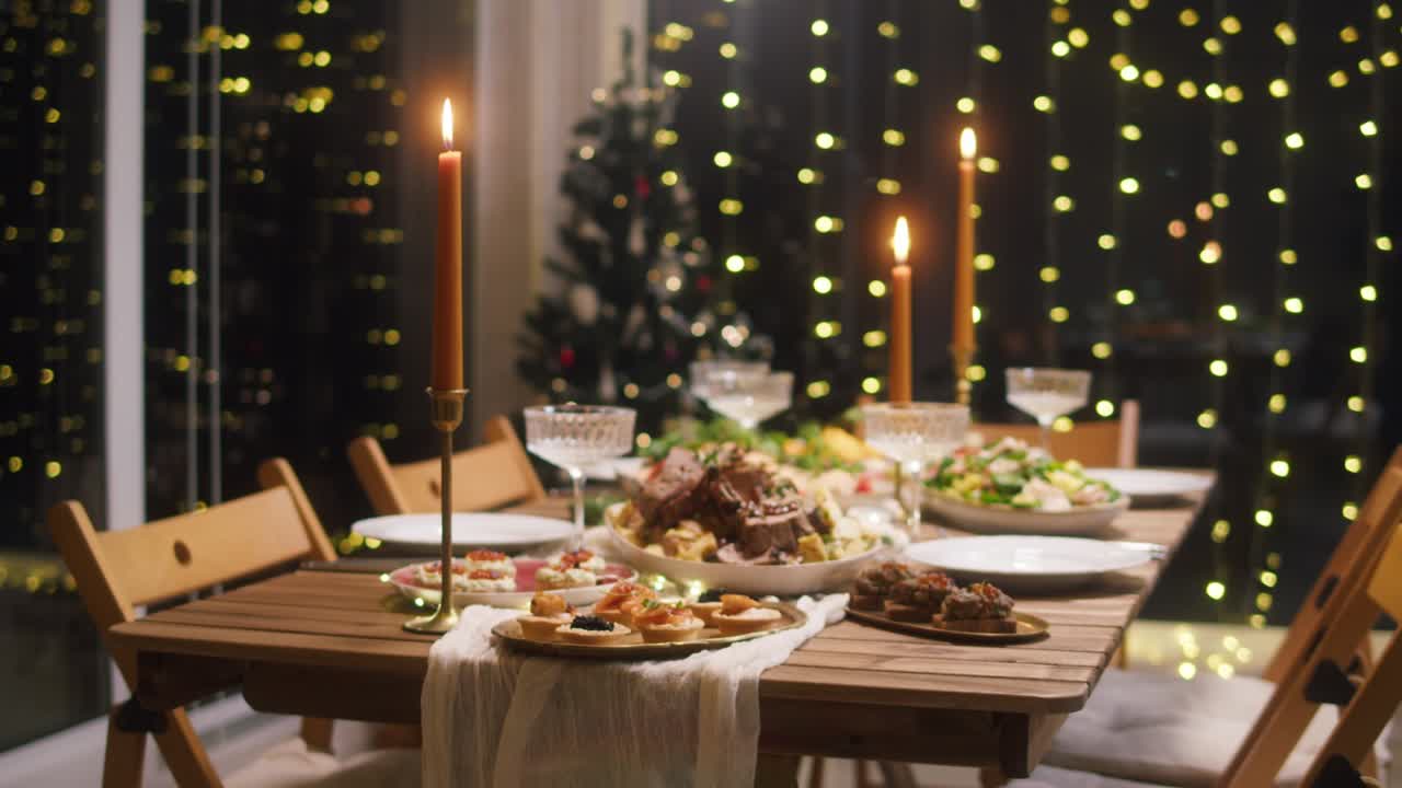 Festive dinner at home, burning candles on dining table. Celebrating new year, delicious dishes, cooked homemade food on plates. Christmas party concept, family tradition.