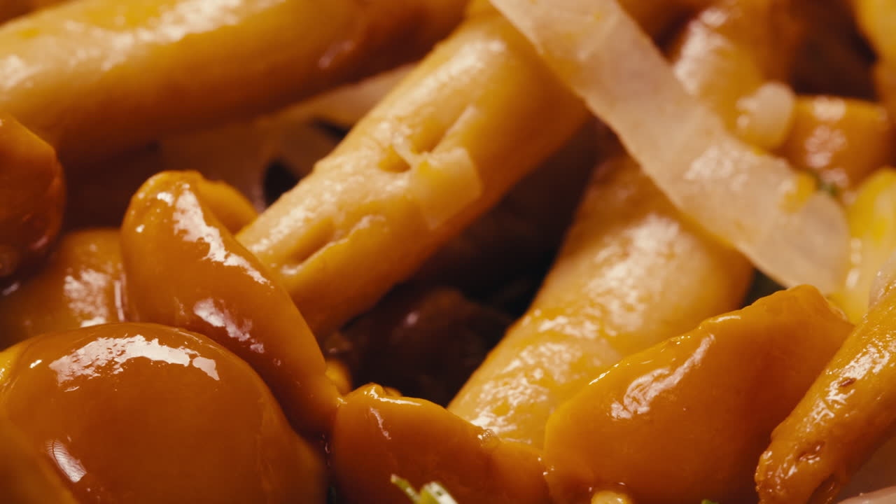 Close-up of fermented yellow honeydew mushrooms with onion on plate. Preservation of vegetables in glass jars. Fermentation preserved mushroom with spices rotating macro.