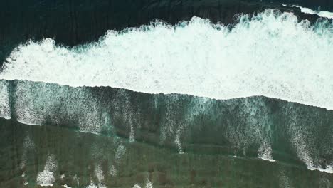 waves crashing into the beach in shelves captured from the air in the beautiful remote holiday location of seychelles