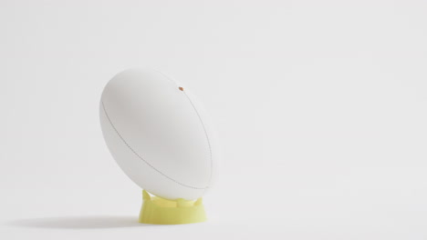 pelota de rugby blanca en patear tee en fondo blanco con espacio de copia, cámara lenta