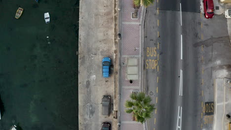 overhead shot of a seaside city harbor street with cars and bus stop