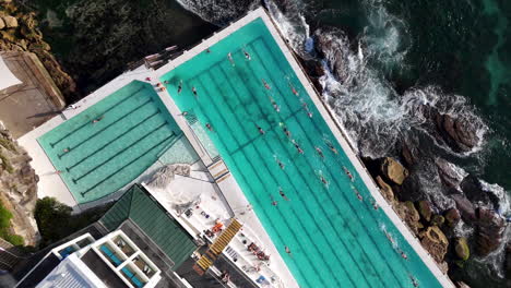 breathtaking drone footage of an ocean pool at bondi beach, australia, with waves gently rolling on the shore. descending aerial footage.