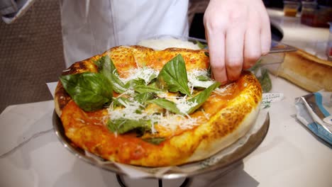 chef adds shredded cheese on top of freshly baked pizza