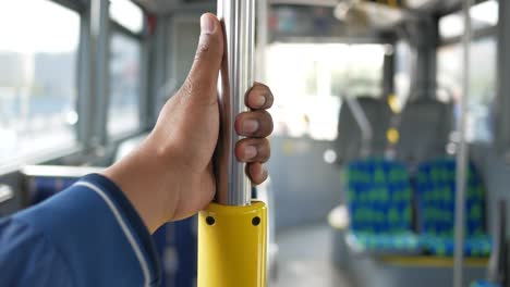 a man's hand gripping a yellow pole on a bus