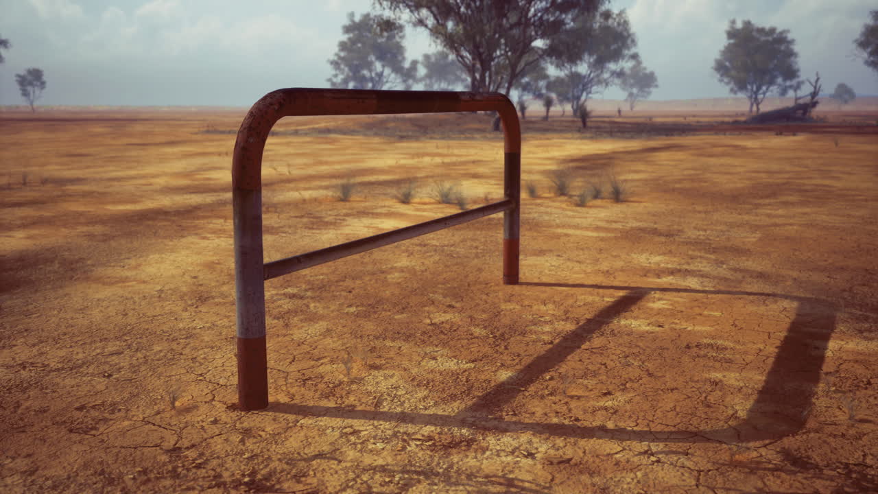 Rusty hurdle set against a cracked dry landscape under a cloudy sky