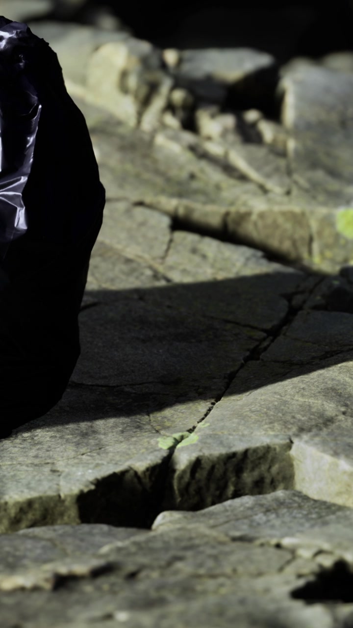 Persona che cammina su un sentiero roccioso tra gli alberi in un ambiente naturale durante il giorno.