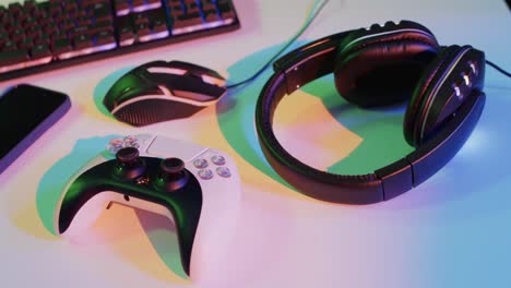 video of gaming computer and gaming equipment on desk with copy space on neon background