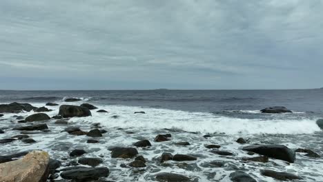 Ocean-waves-rolling-in-over-rocky-bach-and-towards-camera---Aerial-close-to-surface-moving-slowly-ahead-with-vast-and-unlimited-ocean-in-background