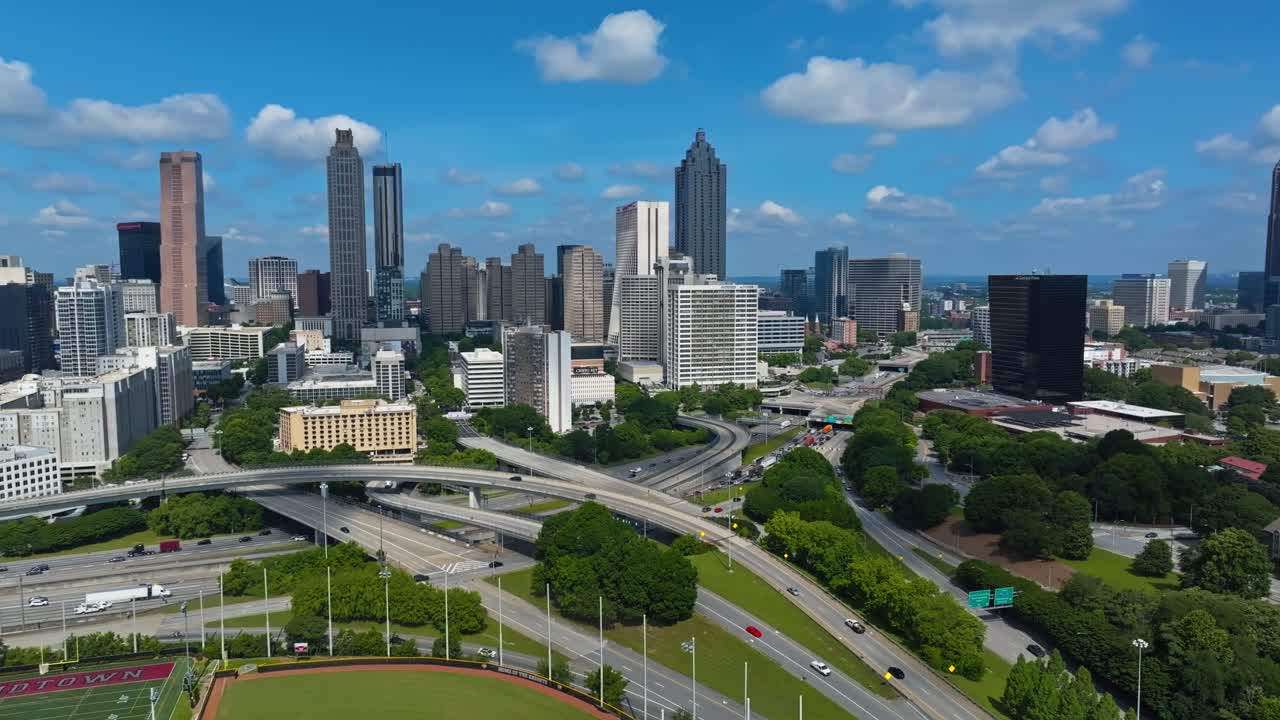 Skyline of Atlanta Downtown with skyscraper ad traffic on multi level highways. Sunny day with blue sky in summer. Football field and stadium in foreground. Georgia, USA. Aerial panorama view.