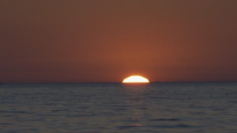 the sun is setting at the croatian seaside in summer above gentle waves