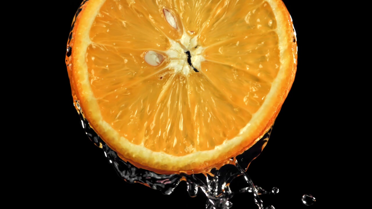 Acqua che gocciola al rallentatore da una fetta d'arancia succosa
