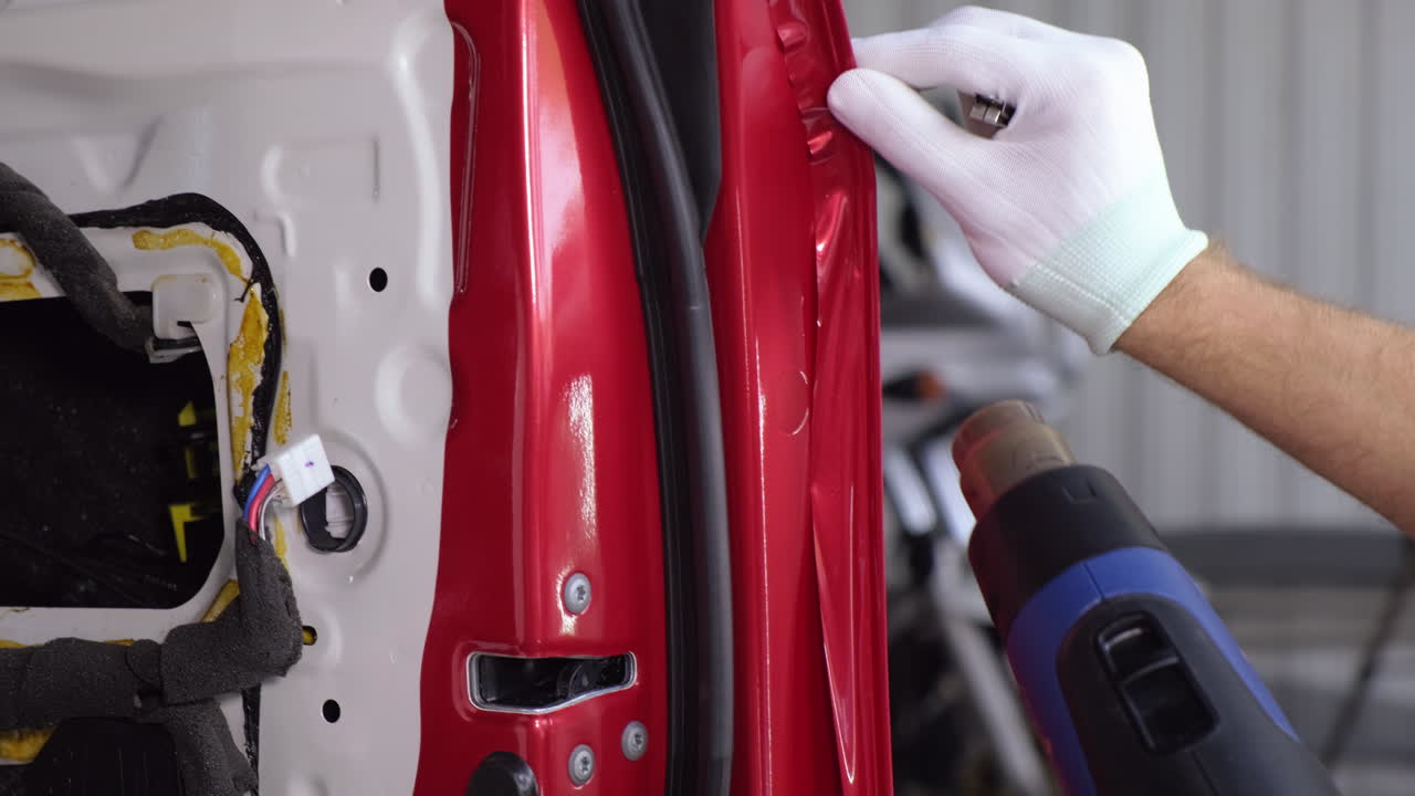 la aplicación de envoltura de vinilo a una puerta de coche con una pistola de calor