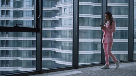 Focused-woman-texting-phone-message-browsing-internet-in-business-office-window.