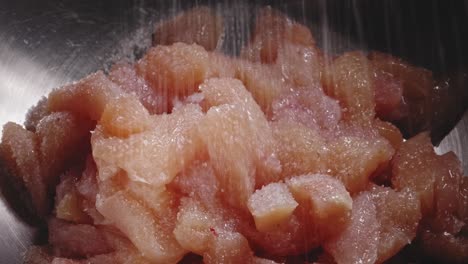 seasoning chicken meat in a bowl with salt, pepper, and herbs