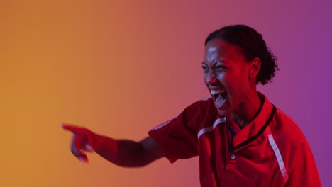 Happy-african-american-female-rugby-player-raising-hands-over-neon-pink-lighting