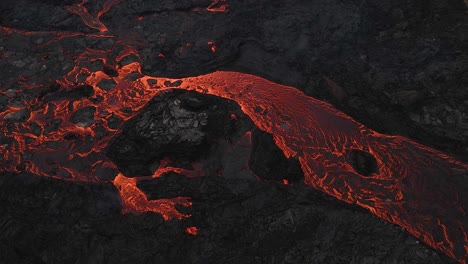 río de lava roja que fluye lentamente a través de rocas solidificadas negras