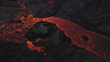 red lava river flowing slowly through black solidified rocks