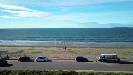 garrylucas sandy beach drone flight over family playing on the beach and coastal road, ireland