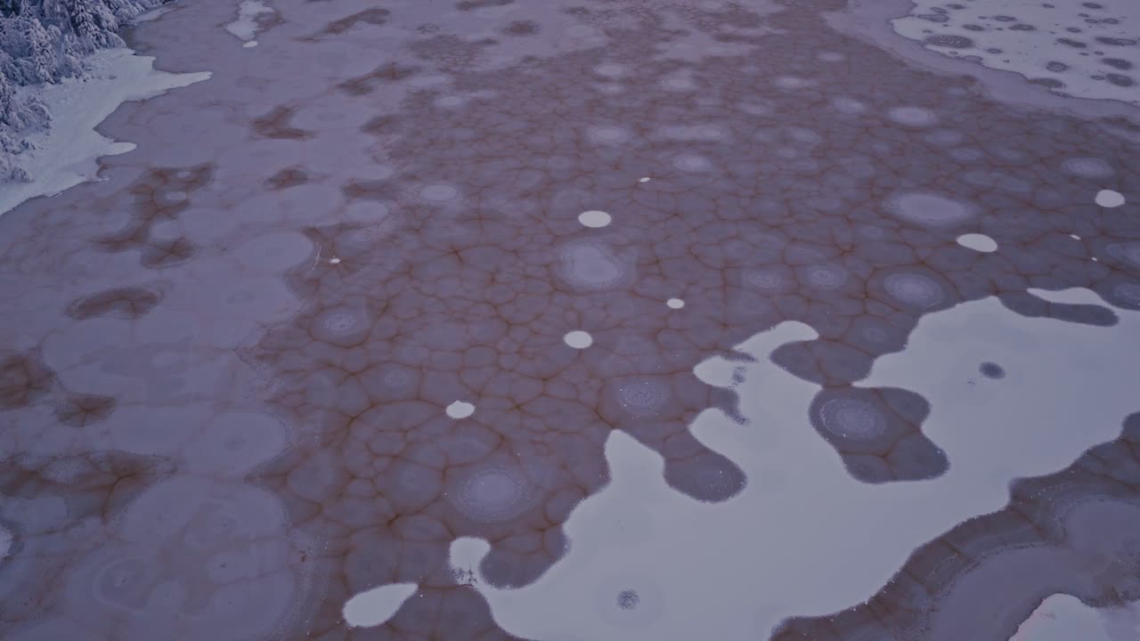 Formaciones de hielo circulares extendidas en un lago parcialmente congelado - Drone volando hacia adelante.