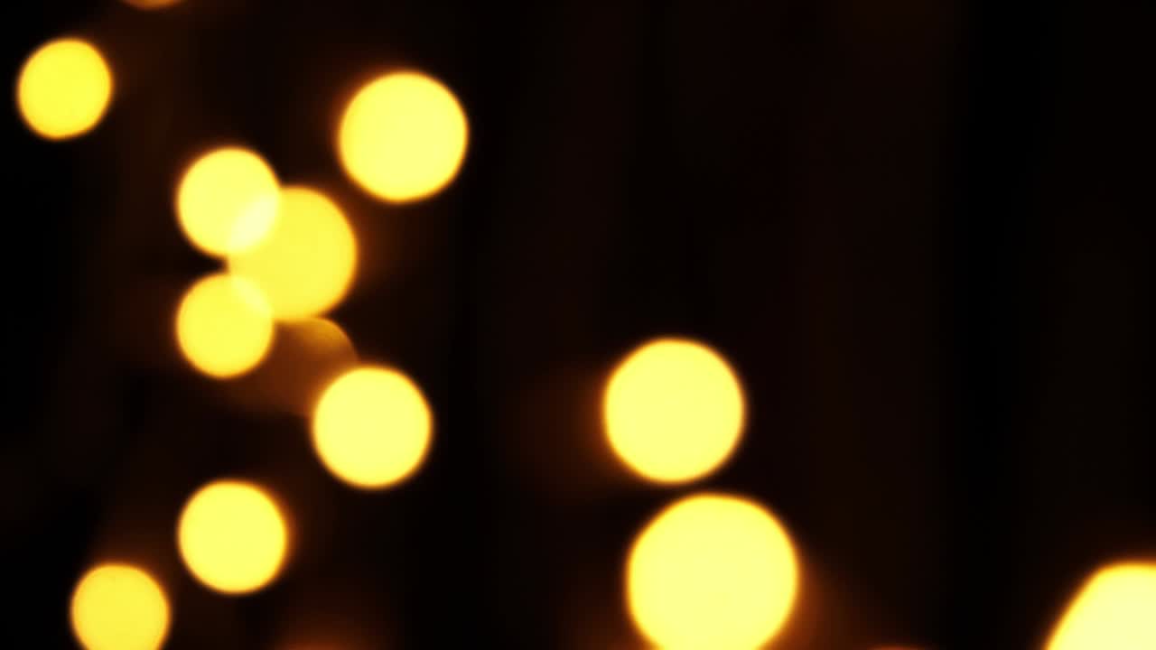 fondo bokeh abstracto en movimiento. brillantes, partículas doradas borrosas, luces. bokeh brillante de guirnaldas en fondo oscuro. telón de fondo festivo de año nuevo o navidad