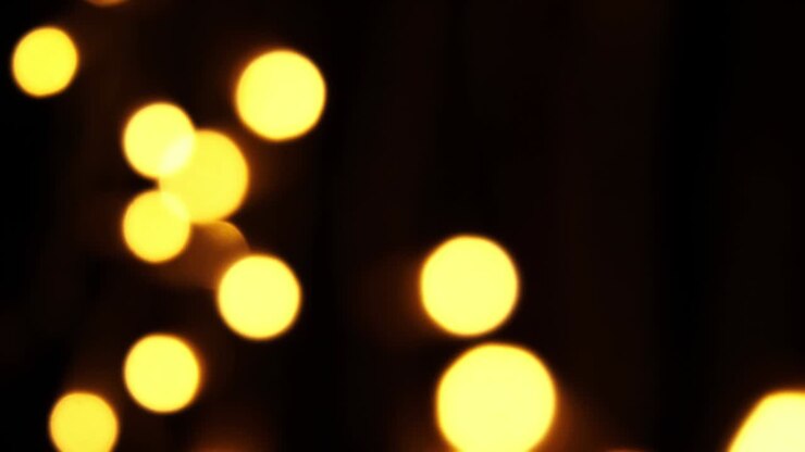 Abstract bokeh background in motion. shining, blurred golden particles, lights. bright bokeh from garlands on dark background. New year or Christmas festive backdrop