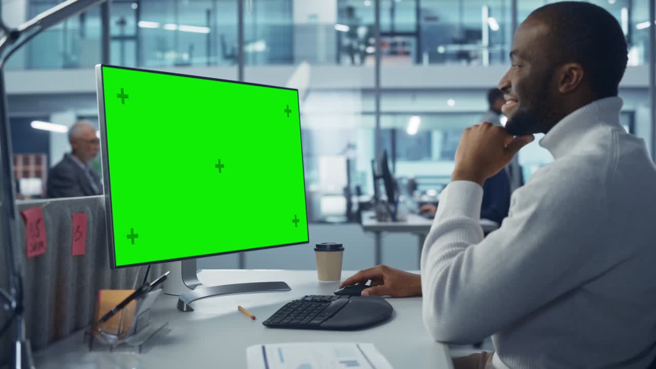 Ufficio moderno e diversificato: Affascinante tecnico IT di colore che usa un computer desktop con schermo verde Chroma Key. Ingegnere amministratore lavora su sviluppo e-commerce, marketing di progetto, analisi di Big Data