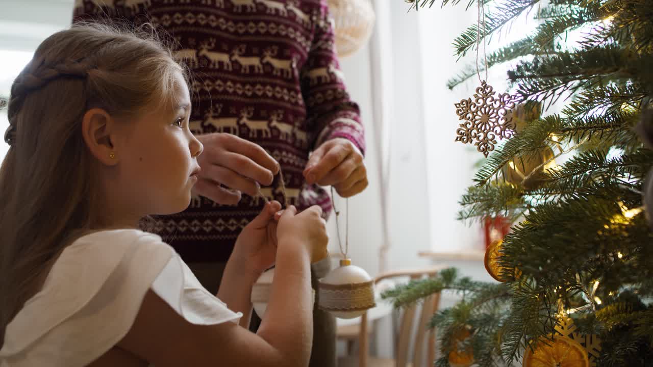 niña con papá decorando el árbol de navidad