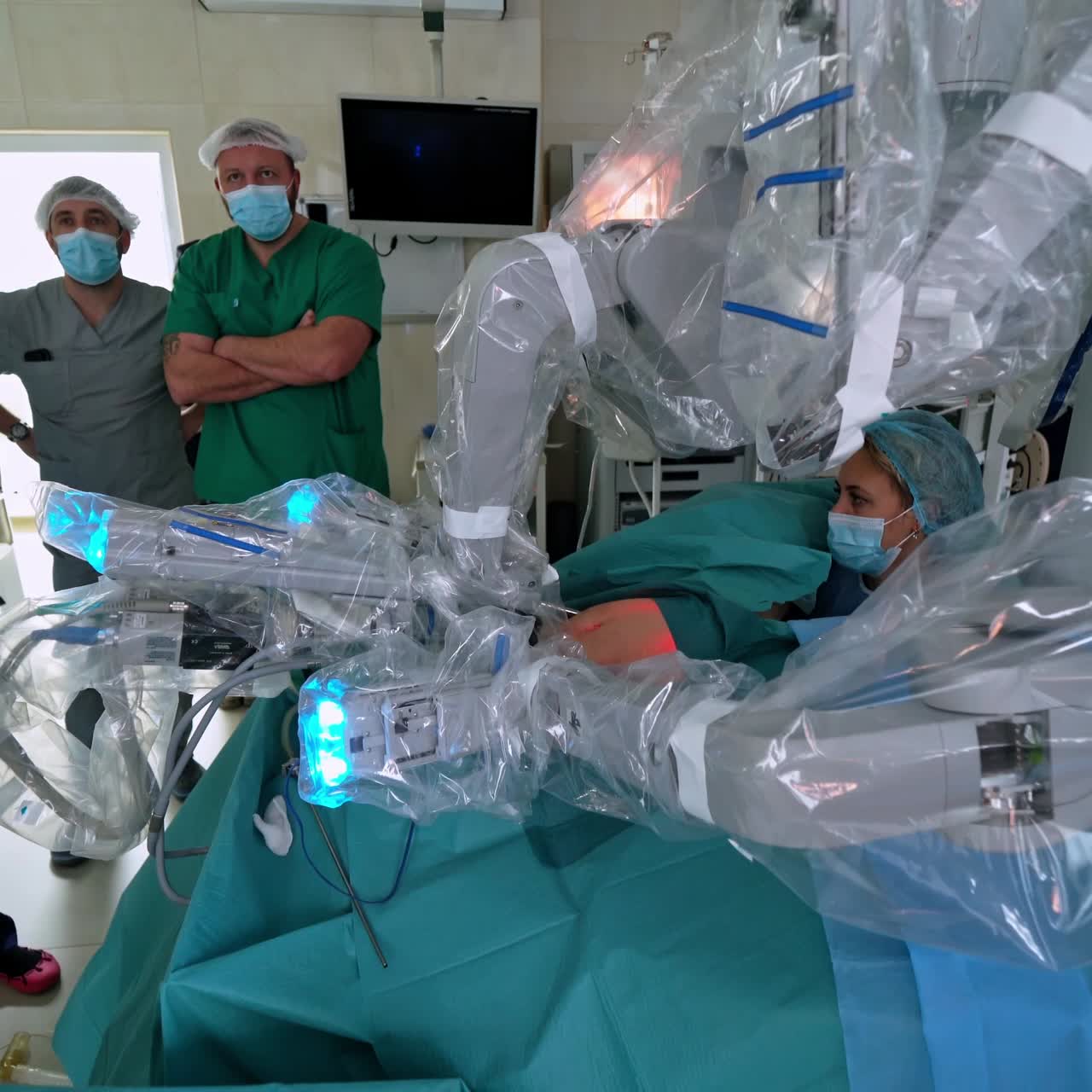 Robotic technology equipment in clinic. Automated arms perform surgery in operation room. Minimally invasive surgical innovation. Doctors observe the work of robotic equipment.