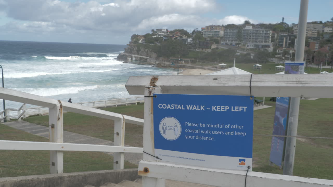 valla de paseo costero de la playa de bronte con signo de distanciamiento social - brote de coronavirus en sydney, nsw, australia