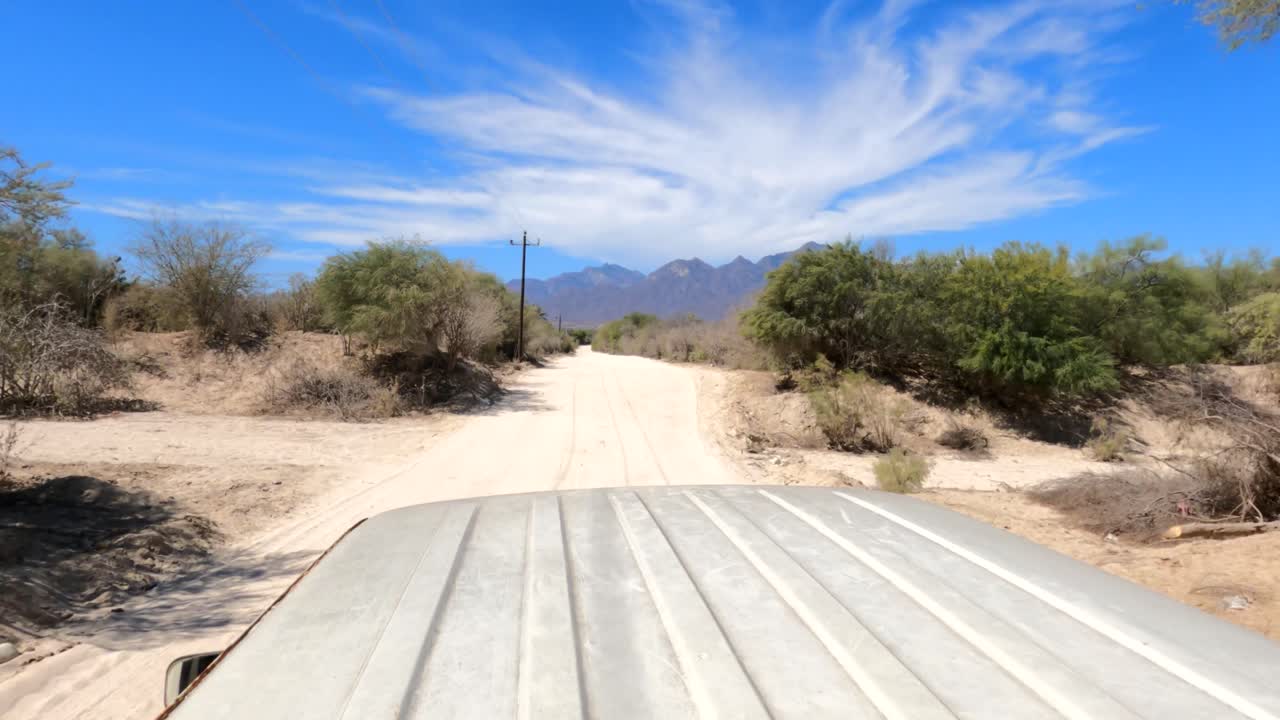 Riding in the back of a pickup truck into the hot desert in Mexico towards the distant foothills to hike