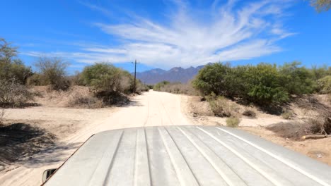 riding in the back of a pickup truck into the hot desert in mexico towards the distant foothills to hike