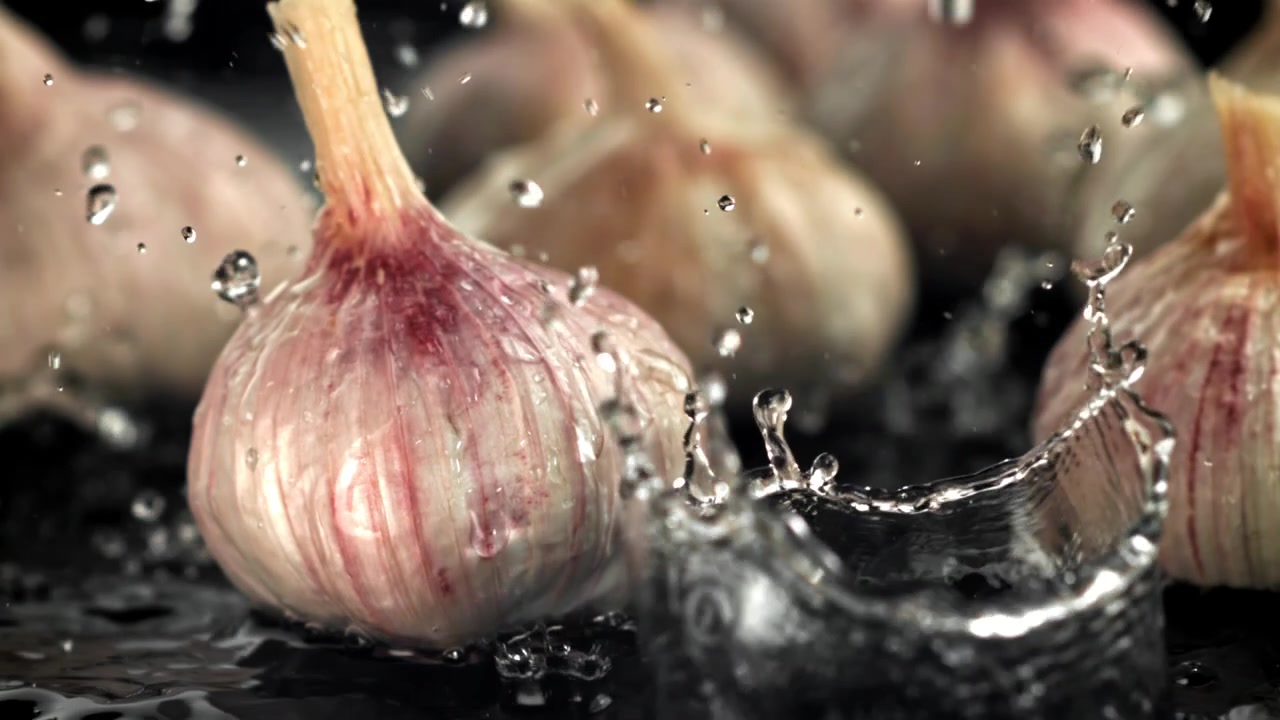 Bulbi d'aglio freschi con schizzi d'acqua al rallentatore